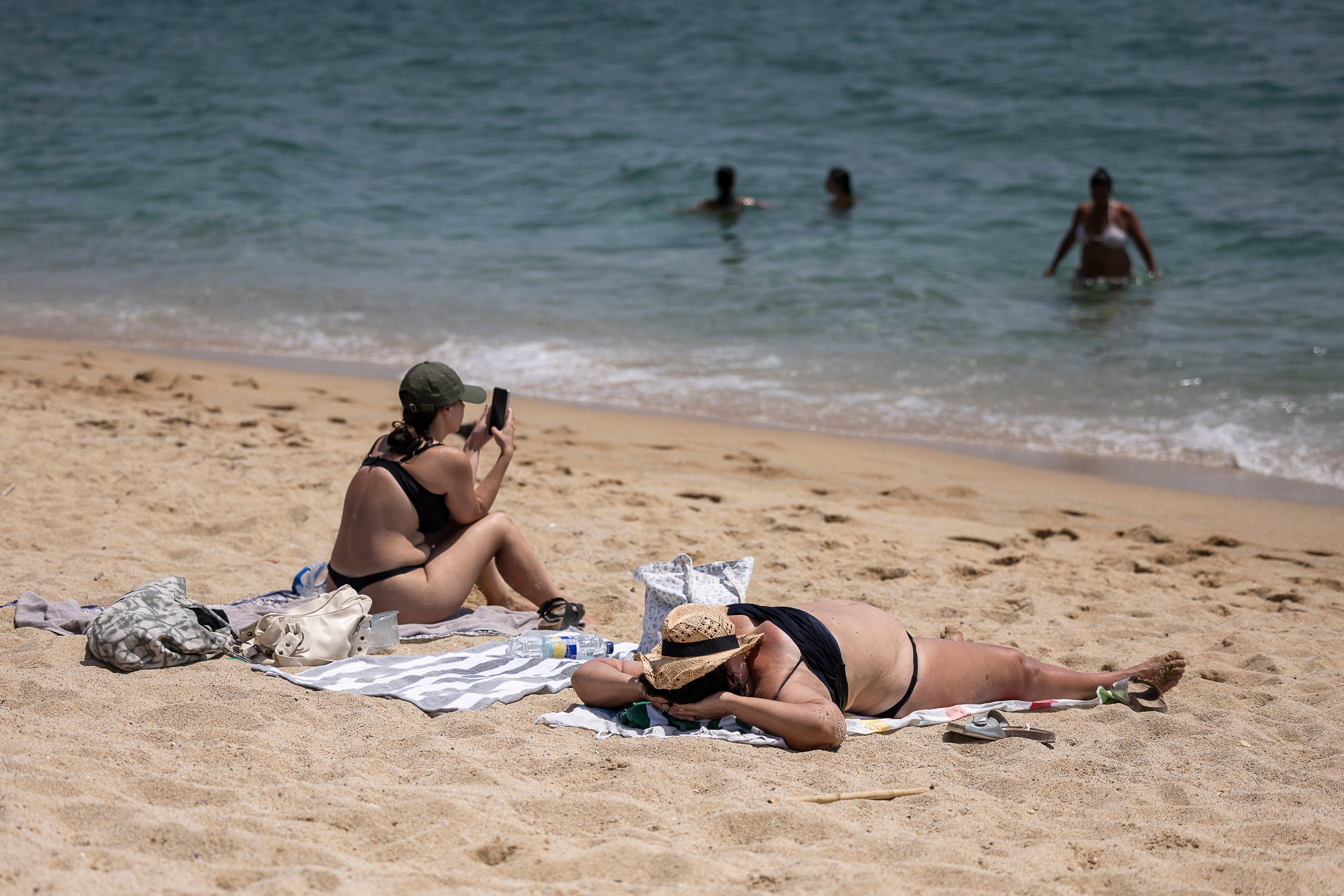 Dos mujeres toman el sol en la playa de les Barques de Montgat, en Barcelona, el 31 de julio de 2026.