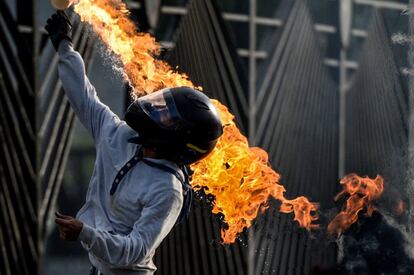 Un activista opositor del presidente Nicolás Maduro lanza un cóctel molotov furante las protestas frente a la base aérea en Caracas.