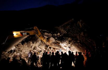 Los equipos de rescate trabajan de noche frente a una casa derruida, en Pescara del Tronto.