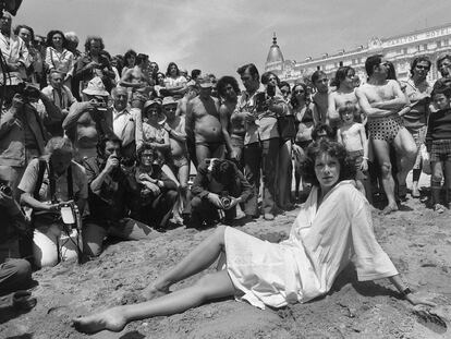 Sylvia Kristel posa en la playa de Cannes en 1977 rodeada de hombres que observan.