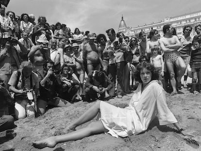 Sylvia Kristel posa en la playa de Cannes en 1977 rodeada de hombres que observan.