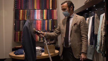 Carlos Satrústegui, propietario de la tienda Leste, desinfecta una prenda probada por un cliente, este lunes.