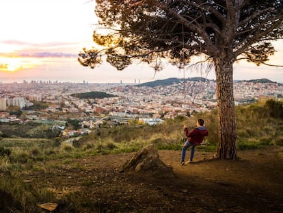 Un joven contempla el atardecer sobre Barcelona desde un columpio colgado de un árbol en las montañas de Collserola.