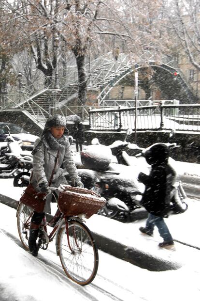 Una mujer marcha con su bicicleta por las aceras nevadas del Canal de Saint Martin, en París.