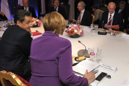 Merkel conversa con Sarkozy, ante Papandreu, durante el encuentro de ayer en Cannes.
