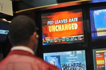 Un corredor de bolsa sigue en una pantalla el comunicado de la Reserva Ferederal estadounidense.