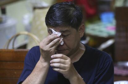 Banphot Konkum, el tío de Duangpetch Promthep, uno de los niños rescatados de una cueva inundada, se limpia los ojos mientras ve a Duangpetch y al resto de los niños en vivo en la televisión.