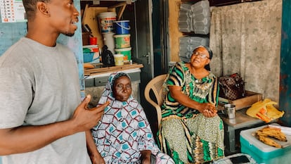 El pastor protestante Justice Obeng, a la izquierda, con dos mujeres musulmanas sentadas a la puerta de su casa en Nima (Accra).