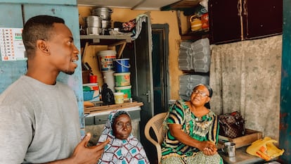 El pastor protestante Justice Obeng, a la izquierda, con dos mujeres musulmanas sentadas a la puerta de su casa en Nima (Accra).