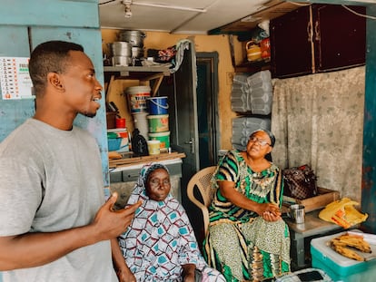 El pastor protestante Justice Obeng, a la izquierda, con dos mujeres musulmanas sentadas a la puerta de su casa en Nima (Accra).