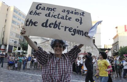 Un aficionado sujeta un cartel durante una actuación callejera: Partido contra el mandato del régimen de la deuda".