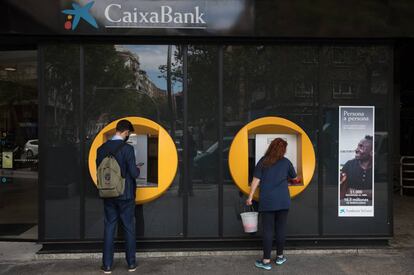 Dvd1020(23/09/20) Una señora  limpia un cajero de CaixaBank mientras un chico realiza una operacion en la calle Orense ,  Pandemia de Coronavirus , Covid19 , Madrid Foto: Víctor Sainz