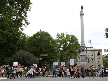 Protesters walk, holding signs, at a ReOpenNC rally against the state's shut down to prevent the spread of coronavirus disease (COVID-19) in Raleigh, North Carolina, U.S., April 21, 2020.  REUTERS/Rachel Jessen