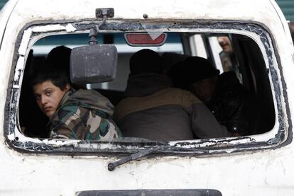 Un soldado sirio mira por la ventana de un vehículo militar destruido.