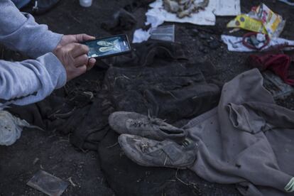 Una persona toma una fotografía de restos de ropa y zapatos encontrados al día siguiente en el lugar de la explosión.