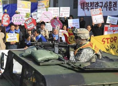 Un soldado estadounidense patrulla por una ciudad de Corea del Sur entre las protestas de activistas.