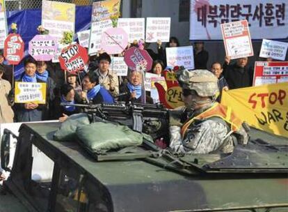 Un soldado estadounidense patrulla por una ciudad de Corea del Sur entre las protestas de activistas.