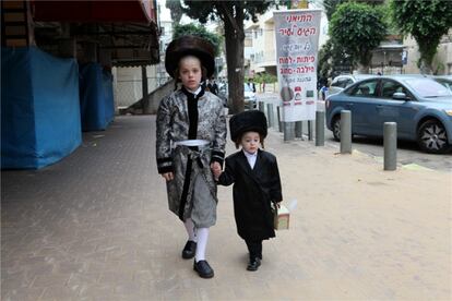 Niños vestidos como adultos, el de la izquierda lleva un atuendo exacto a la ropa de un rabino.