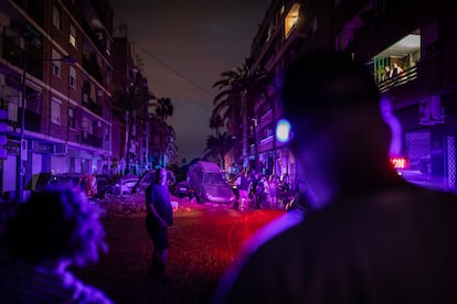 Vecinos de Paiporta caminan sobre el lodo a travs de una calle iluminada por las sirenas de los vehculos de emergencia, en el centro de Paiporta, al anochecer del jueves 31 de octubre de 2024.