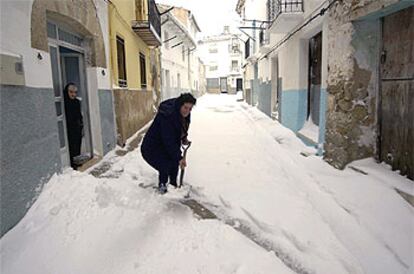 Una mujer retira la nieve acumulada a la puerta de su casa, en Vistabella del Maestrazgo (Castellón).