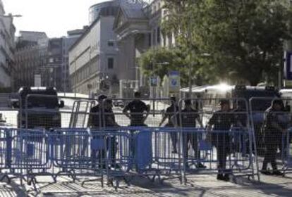 Agentes de la Policía tras las vallas colocadas para impedir el acceso a la zona del Congreso. Varios centenares de funcionarios han iniciado una manifestación esta tarde en las inmediaciones del Palacio de las Cortes, blindado por la Policía, en protesta por los últimos recortes del Gobierno.