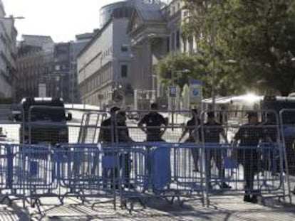 Agentes de la Policía tras las vallas colocadas para impedir el acceso a la zona del Congreso. Varios centenares de funcionarios han iniciado una manifestación esta tarde en las inmediaciones del Palacio de las Cortes, blindado por la Policía, en protesta por los últimos recortes del Gobierno.