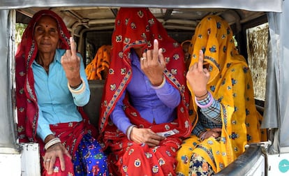 Tres mujeres indias dentro de un rickshaw muestran su dedo marcado con tinta tras votar durante la quinta fase de las elecciones generales de India, en Alwar, estado norteño de Rajasthan.