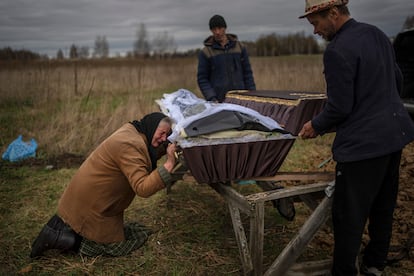 Una mujer llora agarrada al ataúd de su hijo en Bucha (Ucrania).