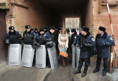 Una mujer pasa junto a una fila de policías que estaban de guardia en el centro de Kiev, mientras los manifestantes de la oposición siguen ocupando la plaza de la Independencia de Kiev.