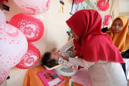 Agentes comunitarios de salud pesan a un bebé en Banda Aceh (Indonesia), este 8 de agosto.
