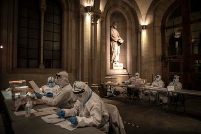 Miembros de mesas electorales con trajes anti-Covid, en un colegio electoral situado en la Universidad de Barcelona, en los comicios del 14 de febrero.