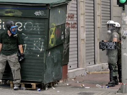 Un manifestante se esconde de la policía tras un kiosco, el pasado miércoles durante una protesta en el centro de Atenas.