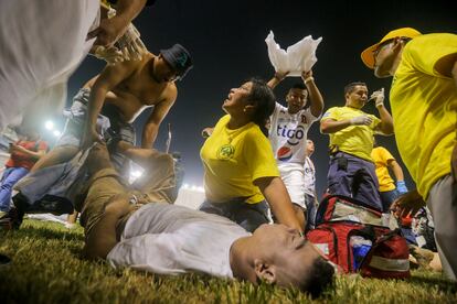 Rescuers attend an injured fan lying on the field of the Cuscatlan stadium in San Salvador