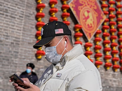 Un hombre vestía una gorra con una bandera estadounidense este jueves frente a unas decoraciones en Pekín.