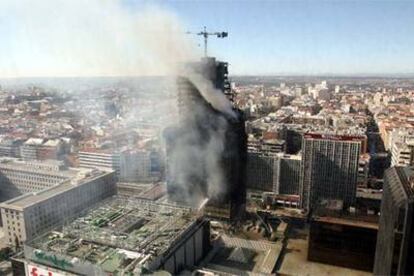 Vista del edificio siniestrado ayer por la mañana, envuelto en humo.