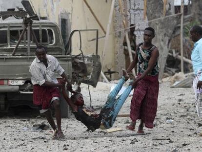 Dos hombres llevan a un herido del asalto de Al Shabab al hotel Al Mukarama de Mogadiscio, el pasado 27 de marzo.