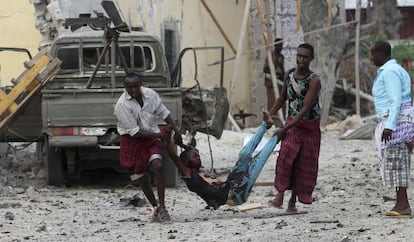 Dos hombres llevan a un herido del asalto de Al Shabab al hotel Al Mukarama de Mogadiscio, el pasado 27 de marzo.