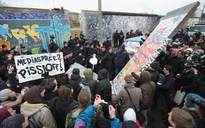 Manifestantes paralizan el derribo, ya comenzado, de un tramo del Muro de Berl&iacute;n e intentan recolocar una r&eacute;plica exacta de la parte demolida en el hueco abierto por los obreros. 