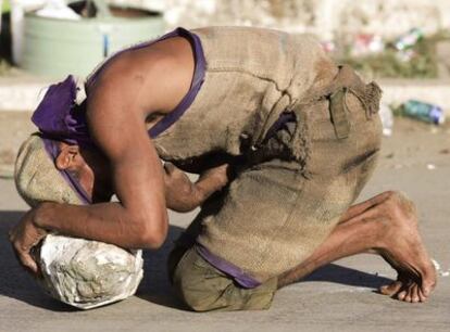 Miles de personas peregrinan anualmente al santuario de San Lázaro, en la ciudad cubana de El Rincón. En la foto, un devoto que hace el camino de rodillas y empujando una piedra, durante una pausa, el jueves.