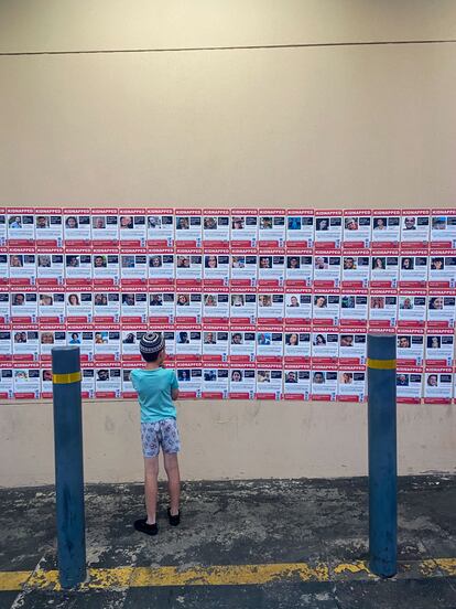 A Jewish child looks at photos of hostages held by the Palestinian Islamist movement Hamas, on a wall in Johannesburg, December 2023.