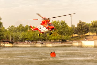 Un helicóptero recarga agua en el lago del parque Juan Carlos I de Madrid, este martes.  