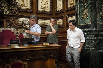 Los operarios apoyan el busto de Juan Carlos I en la mesa que preside los plenos en el Ayuntamiento de Barcelona.