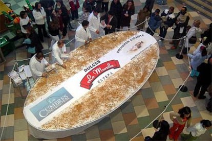 El dulce de Navidad, de 250 kilos, es troceado en un centro comercial de Don Benito (Badajoz).