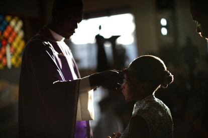 Un sacerdote marca con ceniza la frente de una mujer católica durante una misa de Miércoles de Ceniza en la iglesia de San Juan Bosco en Pétion-Ville (Haití).