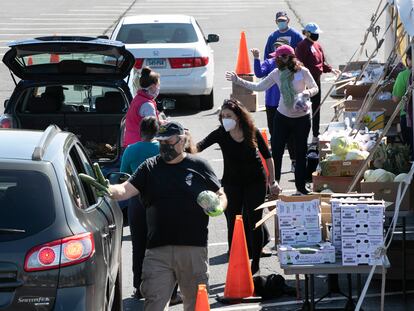 Voluntarios entregan alimentos a vehículos en un centro de distribución en Connecticut, EE. UU. (Foto AP / Mark Lennihan)