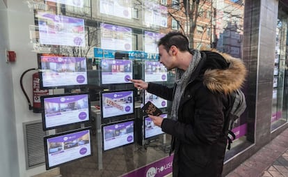 Un joven toma nota de pisos en venta en una agencia inmobiliaria en Madrid. 