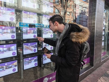 Un joven toma nota de pisos en venta en una agencia inmobiliaria en Madrid. 