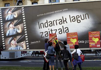 Un piquete informativo pega unos carteles en un panel frente al Kursaal sede del Festival Internacional de Cine de San Sebastián