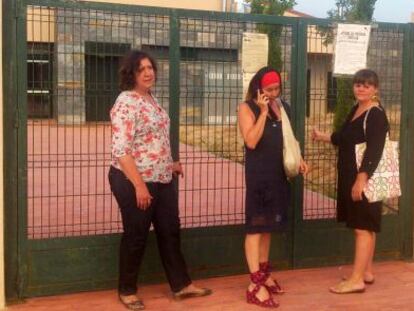 Tres profesoras frente al colegio cerrado.