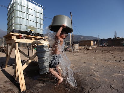 Un niño se da un baño en un asentamiento irregular en Santiago, en una imagen de archivo.